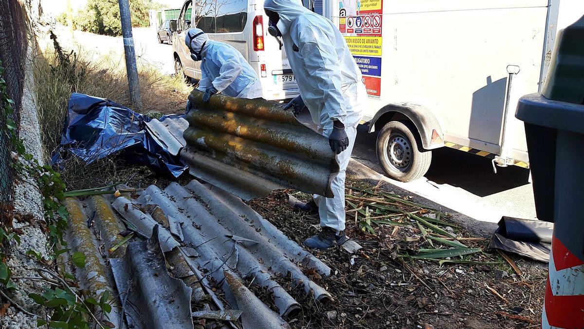 Dos operarios retiran varias placas de uralita de fibrocemento de una cuneta, donde han sido tiradas. | L. O.