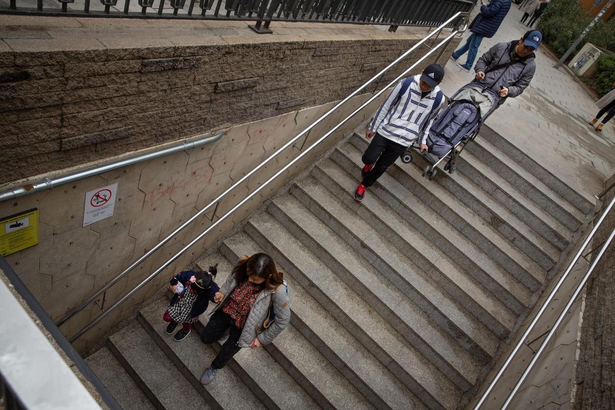 Una familia con un carrito y una mejor bajan por las escaleras de la estación de Plaça de Sants, en Barcelona.