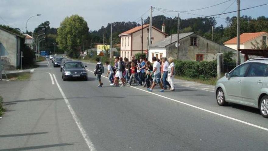 Padres y niños cruzando la N-VI desde la parada del bus escolar en O Carballo. / i.r.