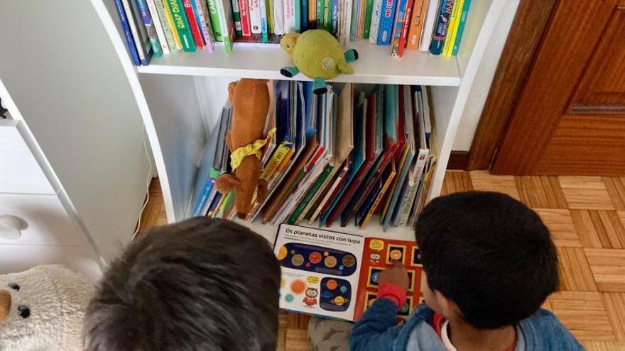 Dous nenos de Infantil antea súa biblioteca persoal. 