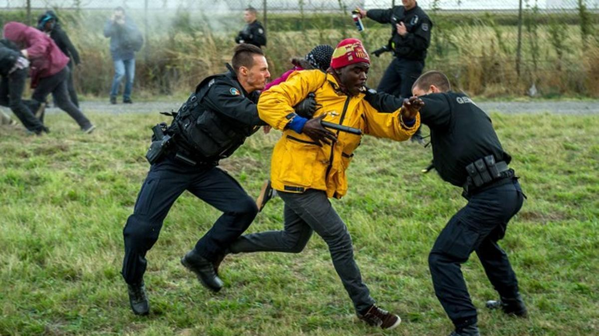 Policías franceses intentan parar a los inmigrantes que buscan colarse al Eurotúnel en Calais este miércoles.
