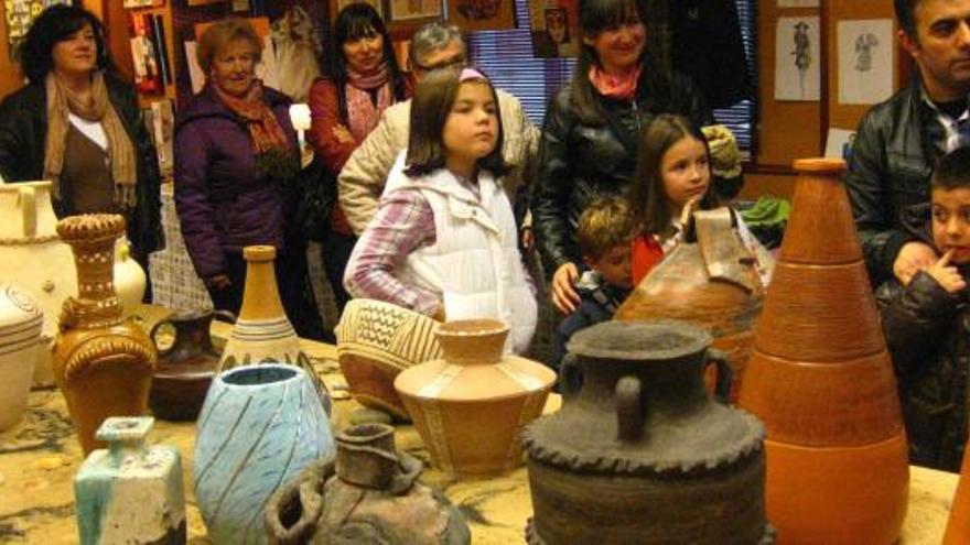 Arriba, ambiente en la exposición de piezas de cerámica. A la izquierda, dos mujeres observan uno de los tapices elaborados en los cursos.