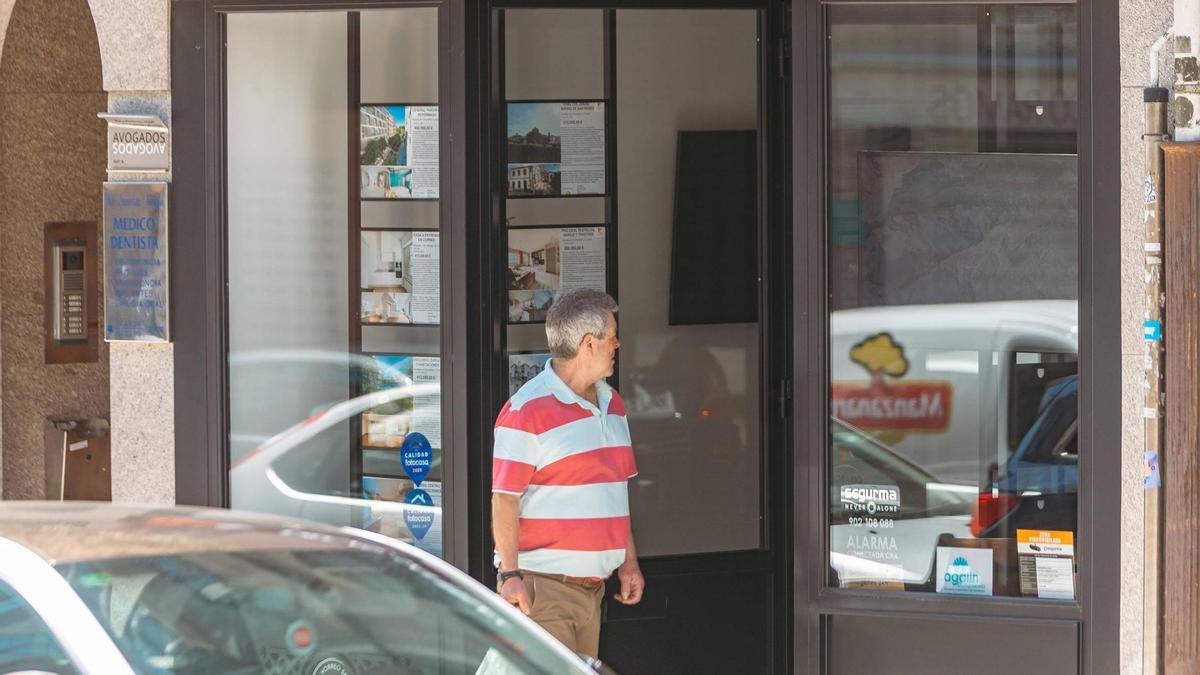 Un señor pasa por delante de una inmobiliaria de Santiago.