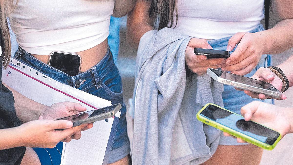 Un grupo de adolescentes con sus teléfonos móviles