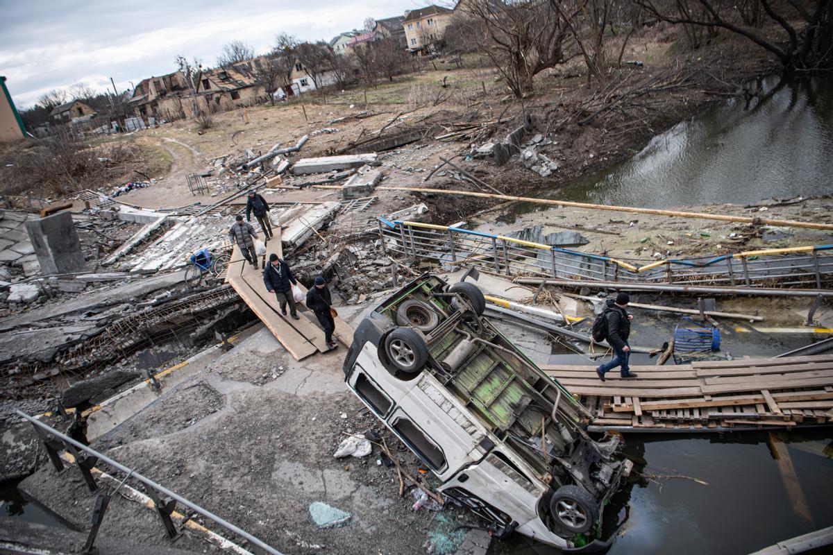 Ucrania, Irpin: La gente cruza un cruce improvisado debajo del puente destruido hacia Irpin, después de la retirada rusa de los pueblos que rodean a Kiev.