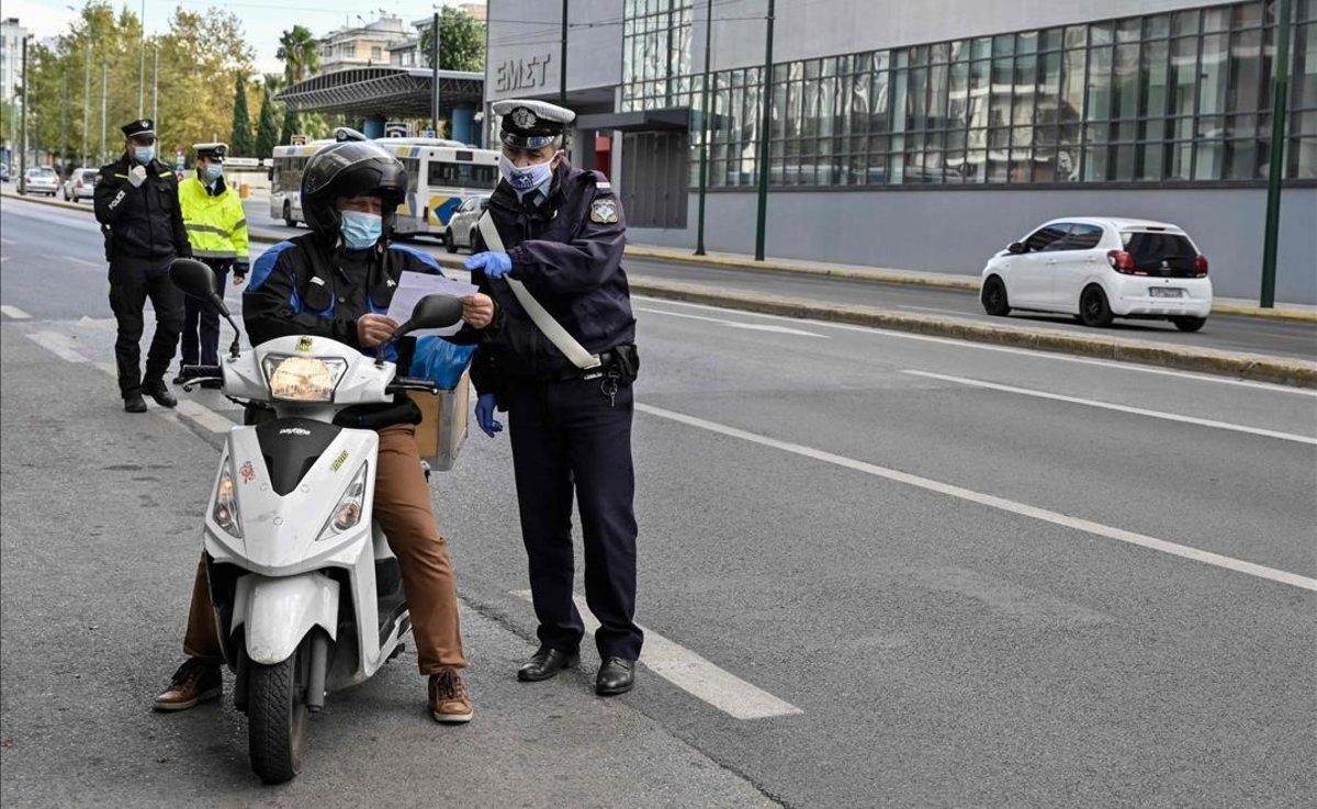 Un agente de policía revisa el permiso de conducir de un motorista en un control en una calle de Atenas.