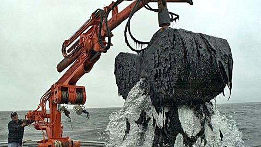 Marineros de la ría de Arousa recogen el petróleo del &#039;Prestige&#039; con la grúa de su barco.