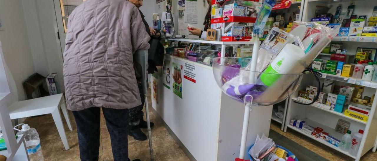 Dos usuarias de la farmacia de Penàguila, atendidas por la boticaria.