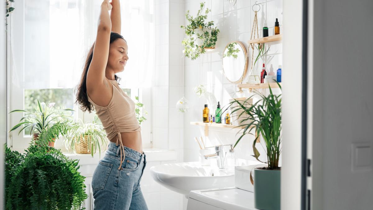 Una mujer se estira en un cuarto de baño lleno con muchas plantas