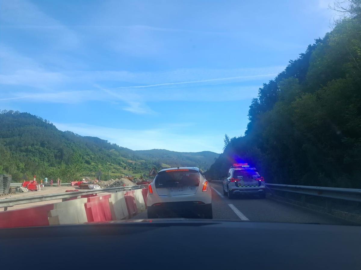 Tráfico lento a la salida del túnel de Fabares dirección Villaviciosa, con un coche de la Guardia Civil en el arcén.