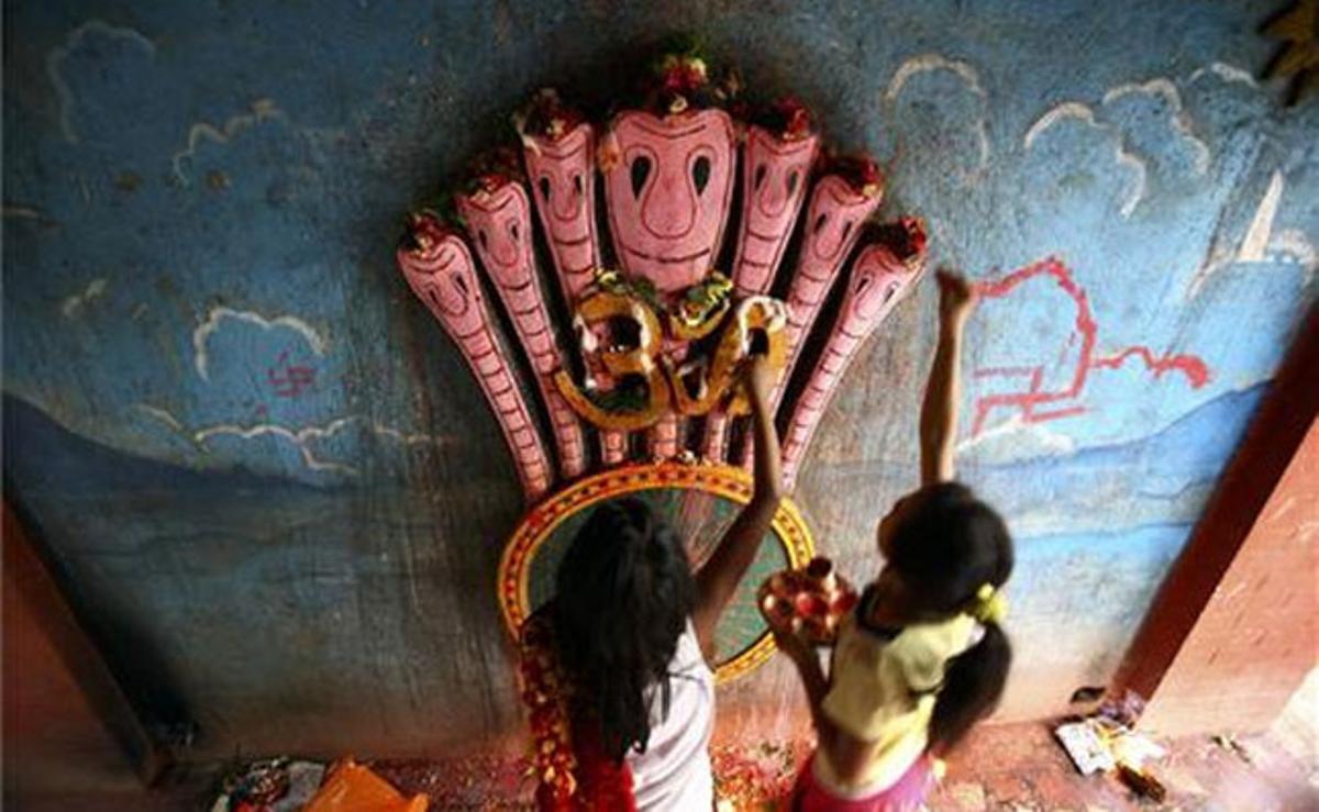 Dos nens adoren una estàtua del déu Serp a Kàtmandu, al Nepal.