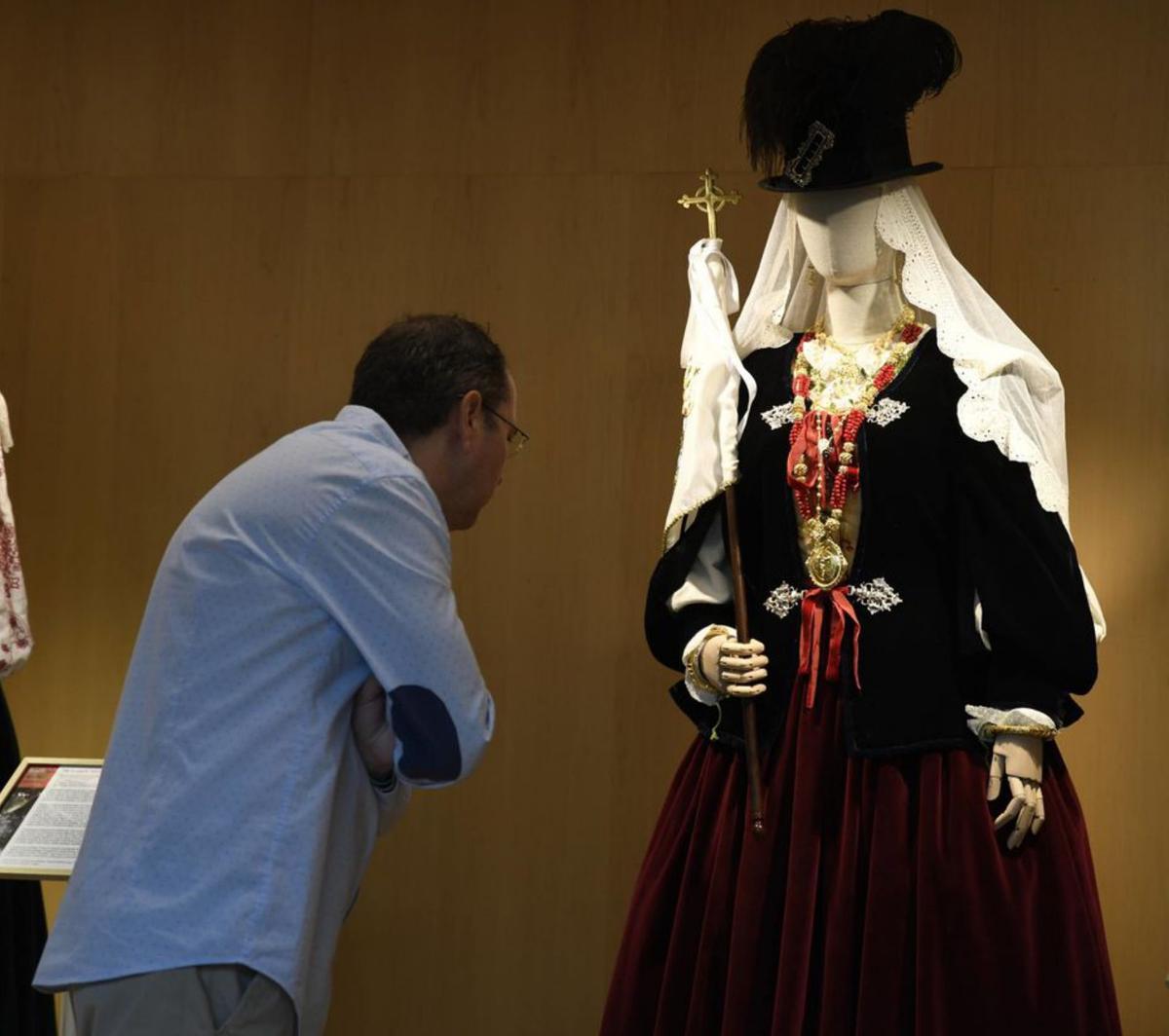 Un hombre analiza el traje de la mayordoma de la Puebla de Guzmán. | M. A. LORENZO