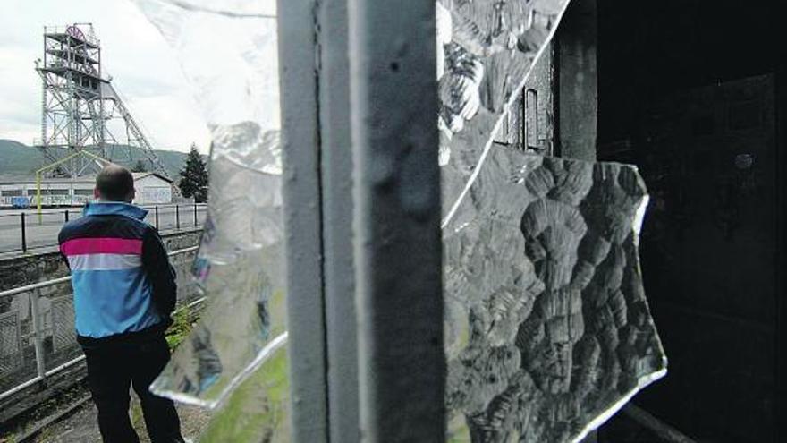 Un joven pasea junto a la casa de aseos de Barredo, con el castillete del pozo al fondo.