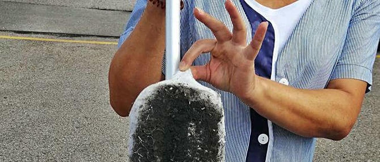 Una limpiadora muestra una mopa llena de polvo negro.