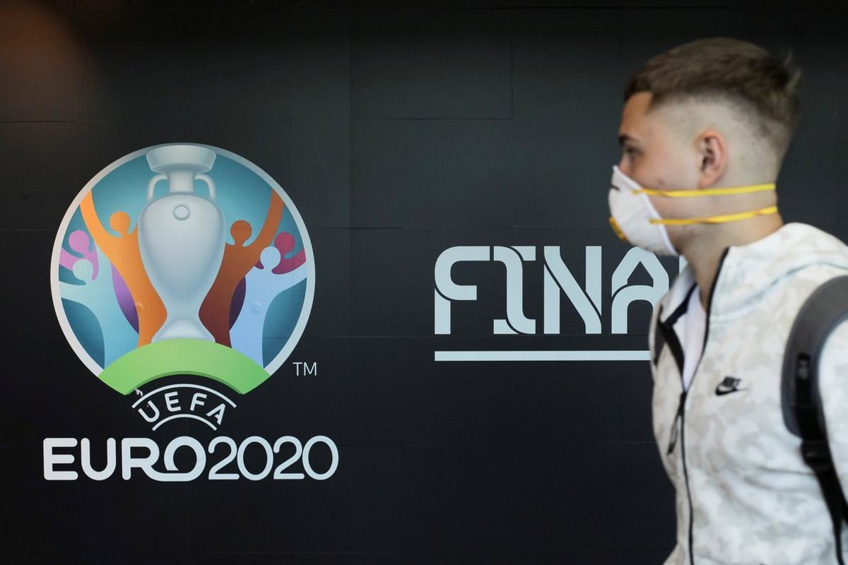 Travellers pass by a logo of the 2020 UEFA European Football Championship displayed on a wall inside Bucharest Henri Coanda International Airport, in Otopeni, Romania, March 16, 2020. Inquam Photos/Octav Ganea via REUTERS ATTENTION EDITORS - THIS IMAGE WAS PROVIDED BY A THIRD PARTY. ROMANIA OUT. NO COMMERCIAL OR EDITORIAL SALES IN ROMANIA