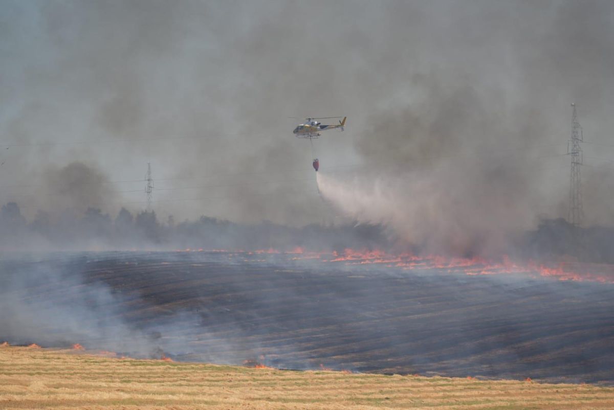 Uno de los helicópteros del Plan Infoex vierte agua sobre el terreno.