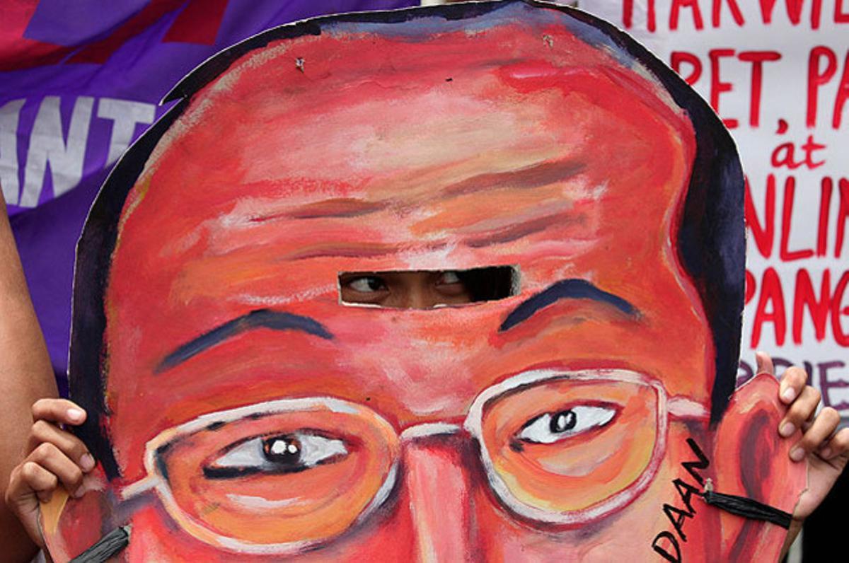 Una dona mira a través d’una careta amb la imatge del president Benigno Aquino III, durant una protesta davant el Palau Presidencial de Malacañang, a Manila.