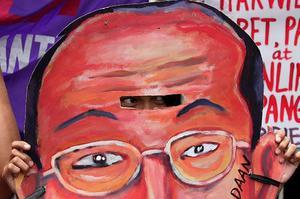 Una dona mira a través d’una careta amb la imatge del president Benigno Aquino III, durant una protesta davant el Palau Presidencial de Malacañang, a Manila.