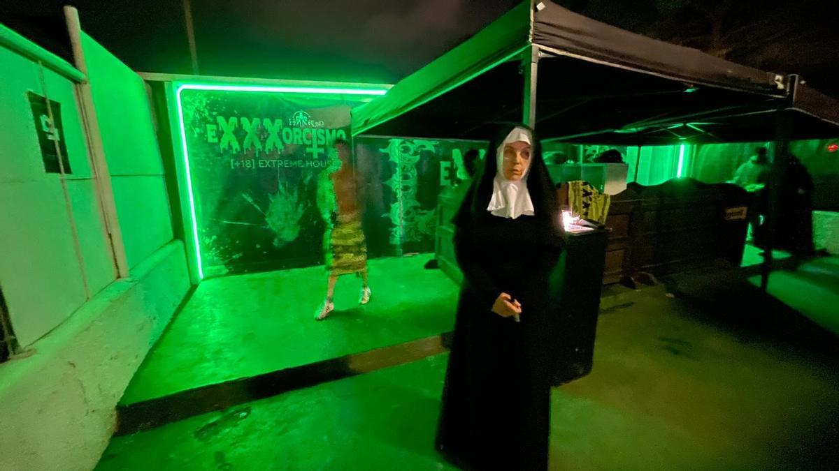 Una monja inquietante vigila la 'extreme house' de Horrorland: Exxxorcismo, con un cliente al fondo cubierto con una toalla.
