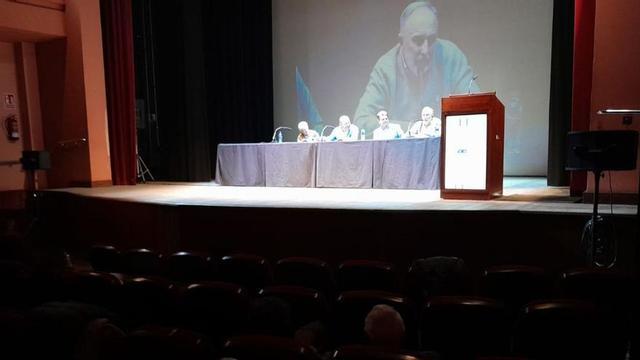 Jesús Montes Sanzo, director del  Coro San Andrés, en la pantalla, se dirige al público asistente. | L. M D.