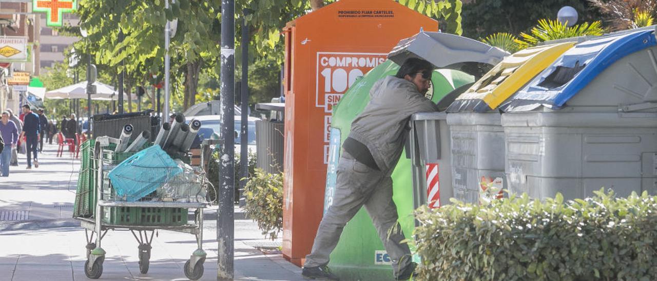 Una persona busca objetos en un contenedor de basura en la ciudad de Alicante, imagen a desterrar a partir de 2021.