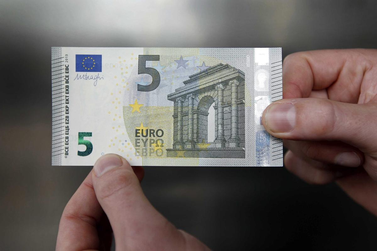 Una persona muestra un billete de 5 euros