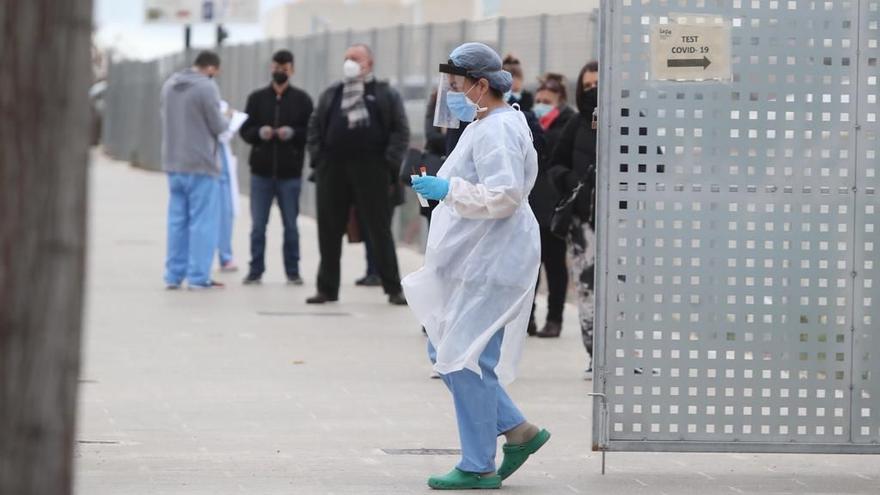 Una sanitaria junto a la cola de pacientes para hacerse una prueba PCR