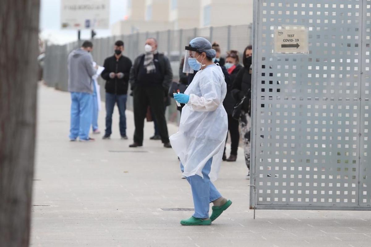 Una sanitaria junto a la cola de pacientes para hacerse una prueba PCR