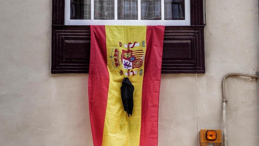 Una bandera con crespón negro cuelga de una ventana en una vivienda de La Laguna.