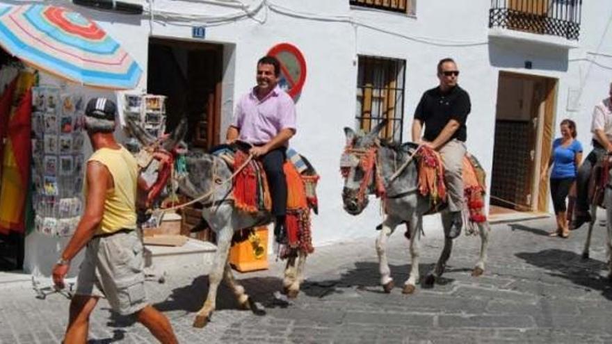 Dos visitantes recorren Mijas pueblo subidos en un burro taxi.