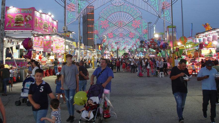 Decenas de personas recorren los puestecillos situados junto a las atracciones de la Feria de Noche.