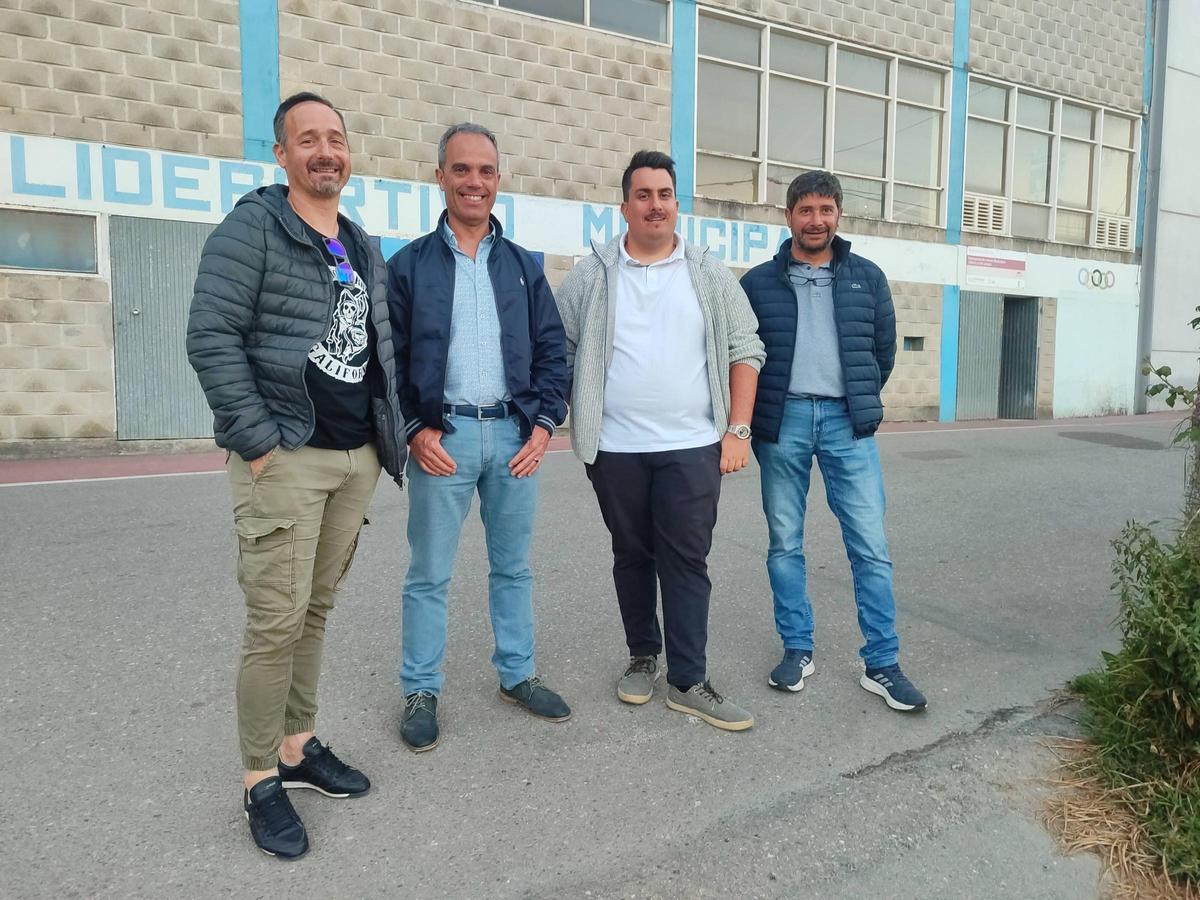 Cuatro representantes de la comunidad energética Romarigo, ante el pabellón que acogerá los paneles solares.