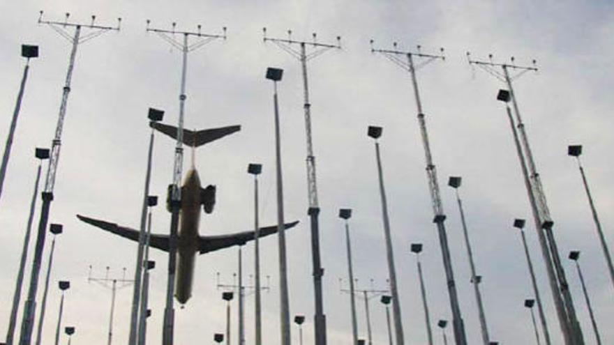 Un avión, sobrevolando el dispositivo antiniebla del aeropuerto.