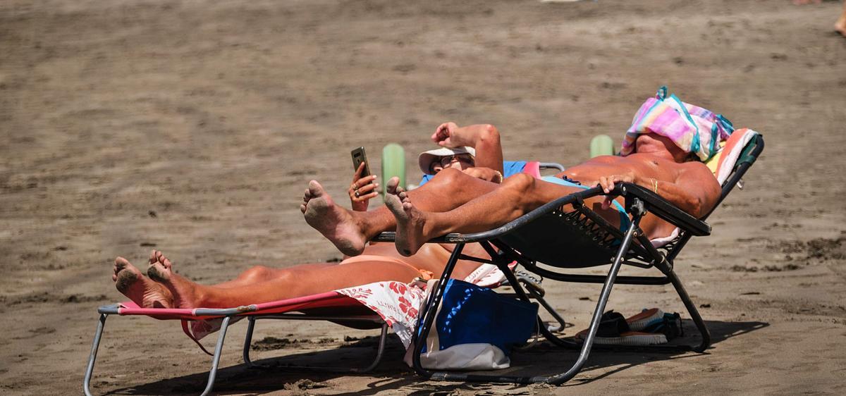 Dos turistas toman sol en la playa de Los Cristianos.