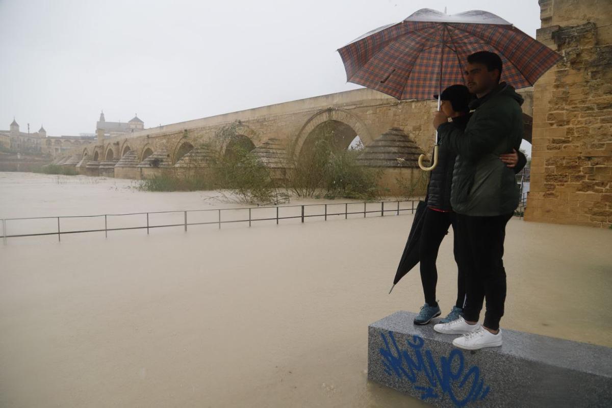 Una pareja junto al río Guadalquivir, desbordado por la crecida