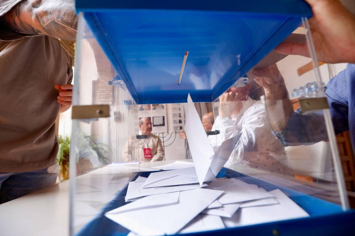 Una persona introduce su voto en una urna electoral.