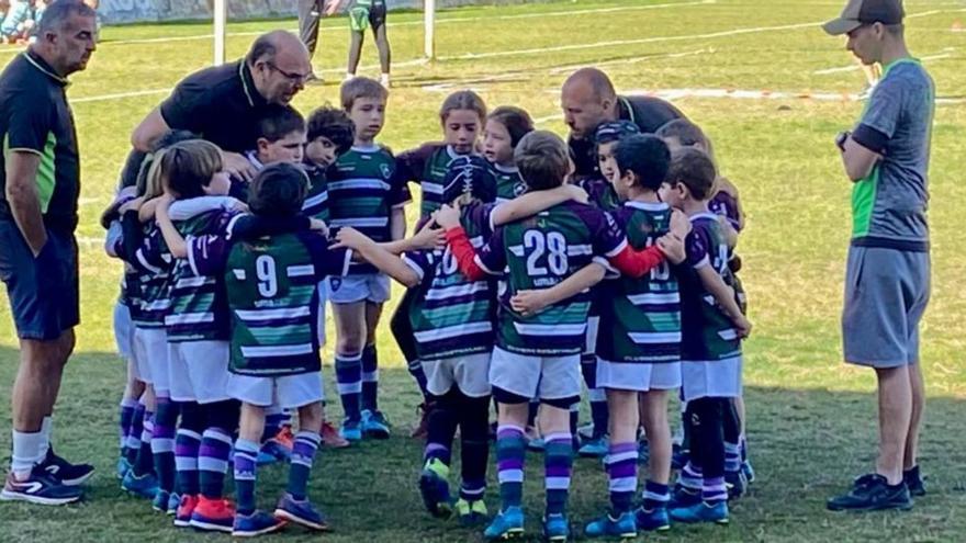 Varios jóvenes jugadores del Club Rugby Málaga rodean a sus entrenadores.