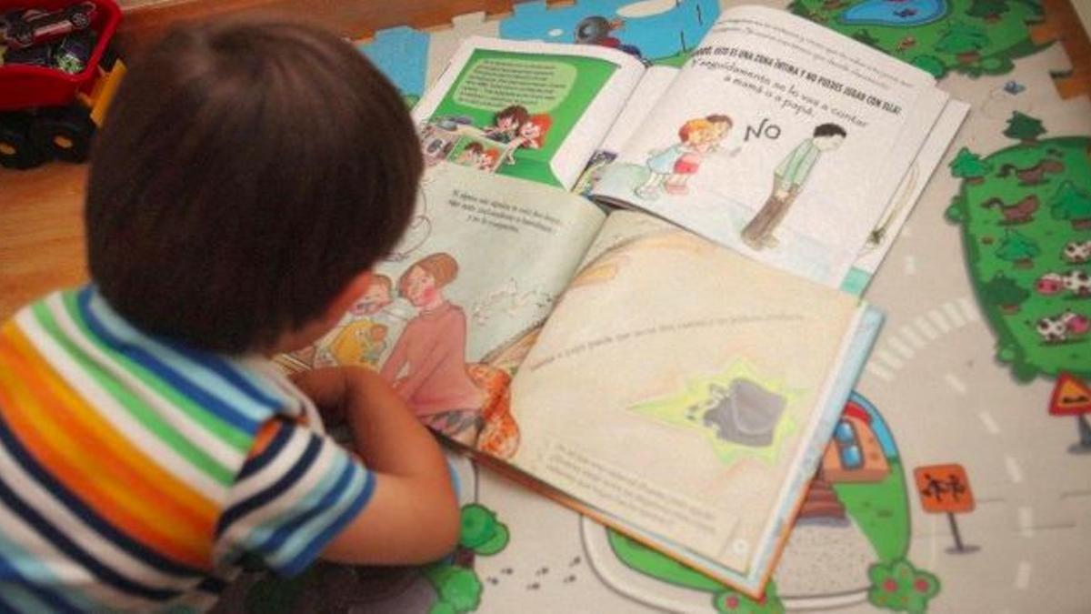 Un niño de tres años mira las viñetas de unos cuentos infantiles para prevenir el abuso sexual, en su casa de Madrid