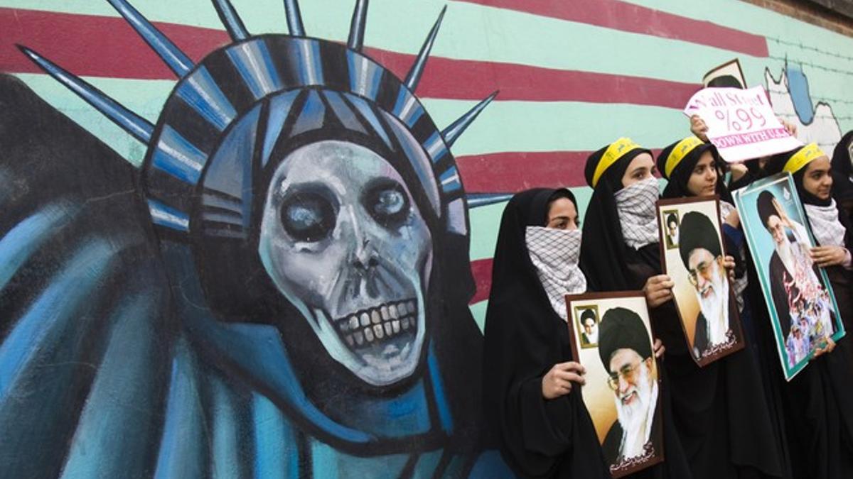 Estudiantes iranís sostienen fotos del ayatolá Jamenei ante el muro de la antigua Embajada de EEUU en Teherán, el viernes, durante los actos de celebración de la toma de la legación estadounidense, hace 32 años.