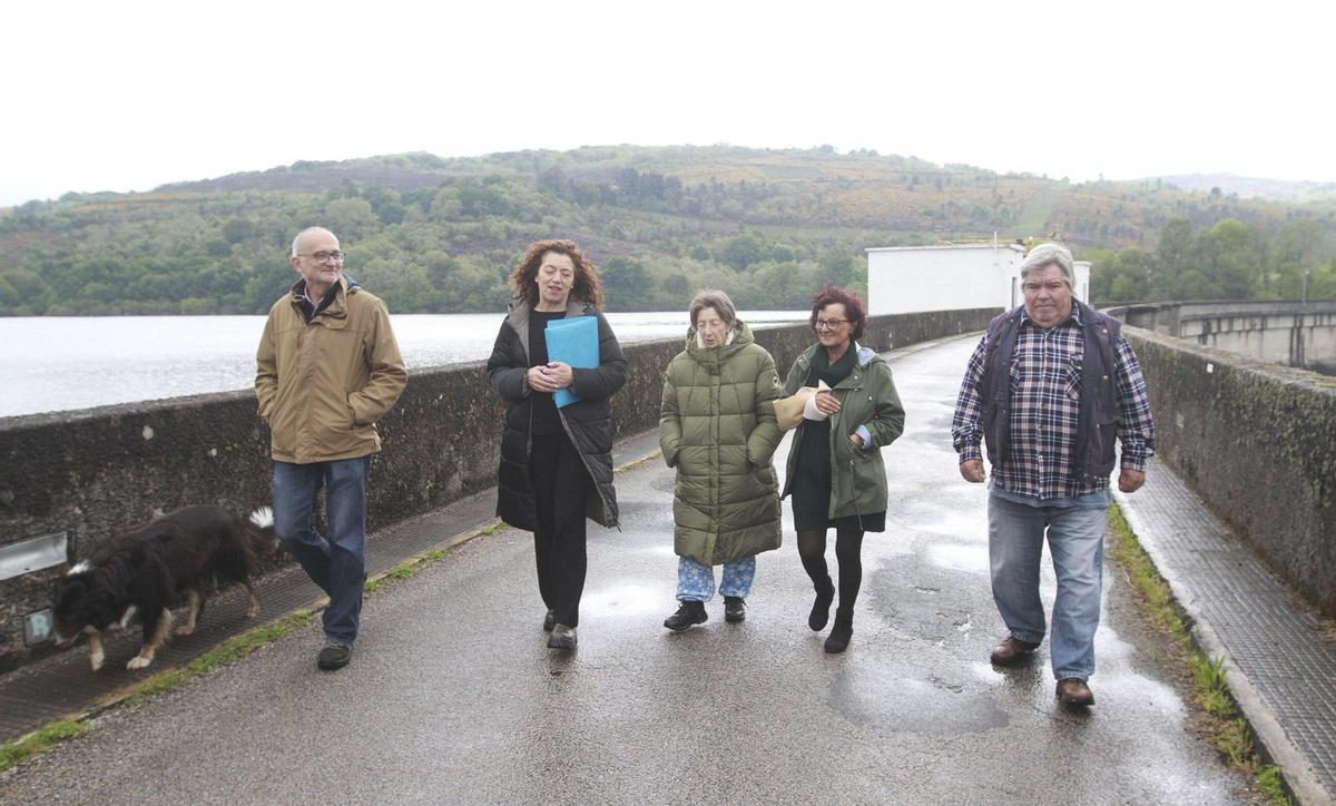 Parte de los vecinos que llevaron a cabo las movilizaciones caminan frente al embalse de As Conchas. | IÑAKI OSORIO