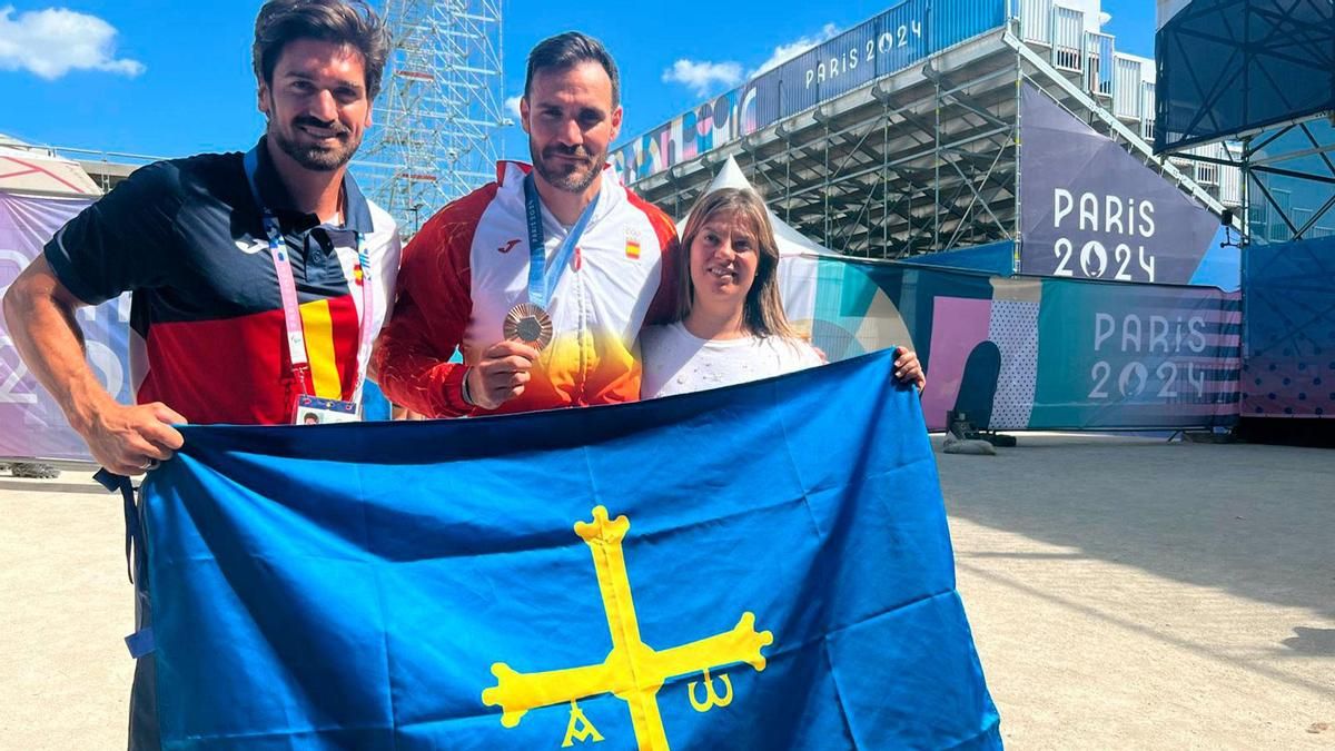 Por la izquierda, Javier Herranz, presidente de la Federación Española de Piragüismo; Saúl Cravioto, con su medalla de bronce, y Gimena Llamedo, vicepresidenta del Principado, ayer, en París, con una bandera de Asturias.
