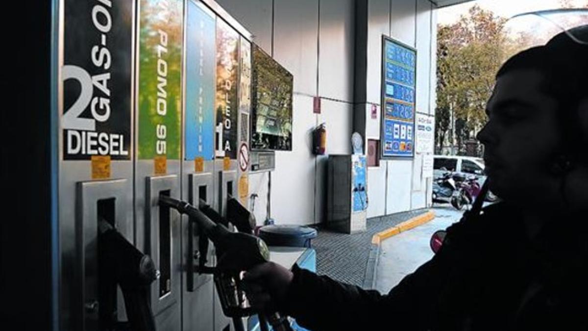 Un cliente se sirve carburante en una estación de servicio de Barcelona.