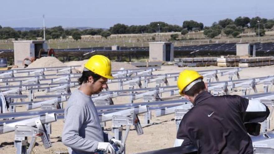 Dos trabajadores montan un parque de placas solares.