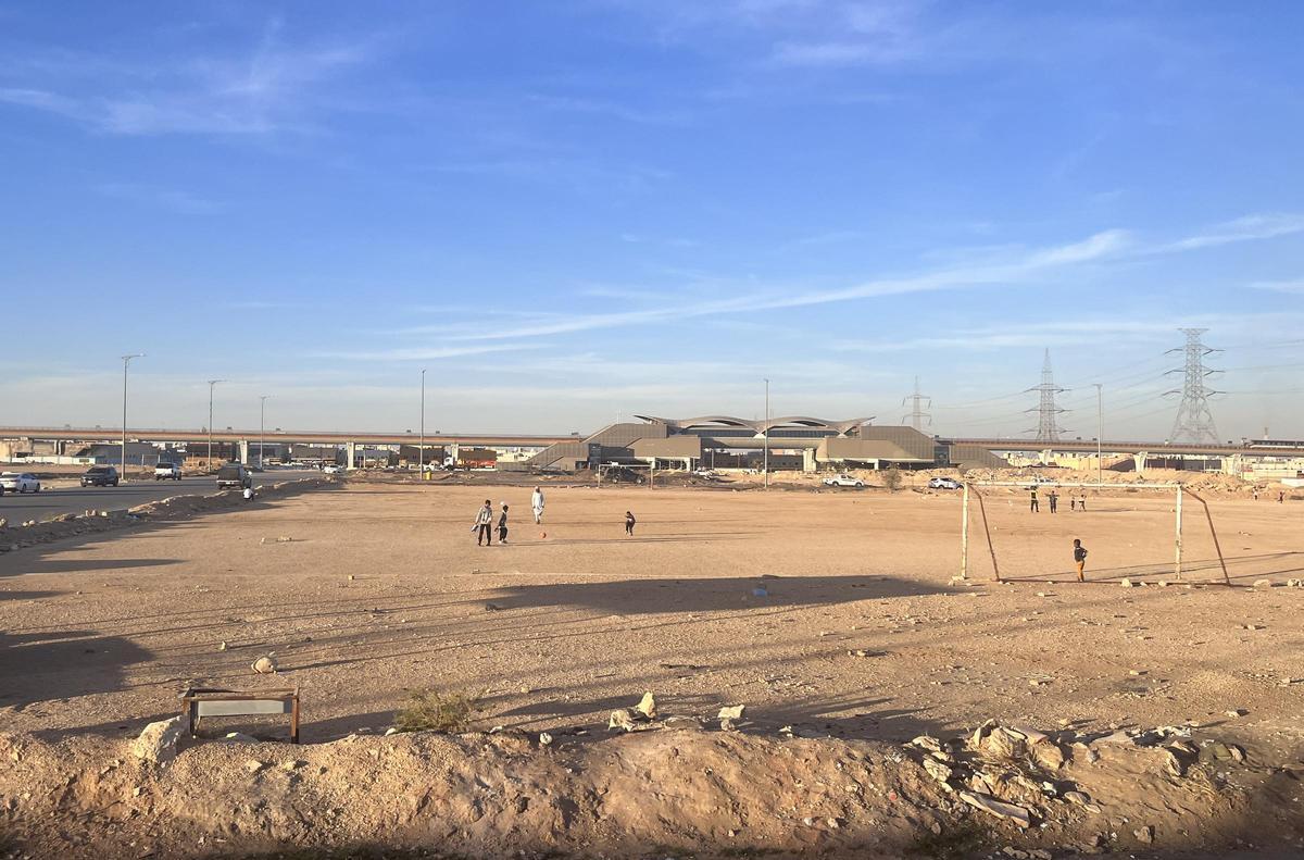 Un grupo de niños juega un partido en un campo de tierra en Riad.