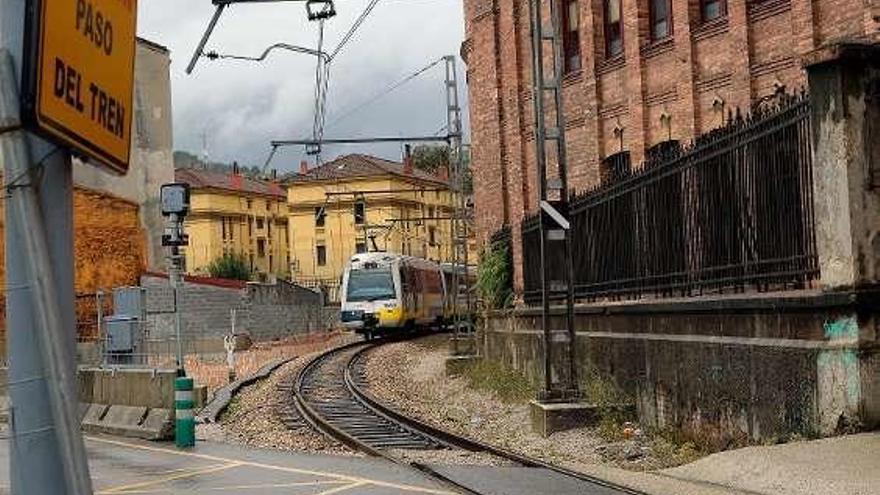 El tren de la línea de Feve circula por las inmediaciones del paso a nivel de Valnalón.