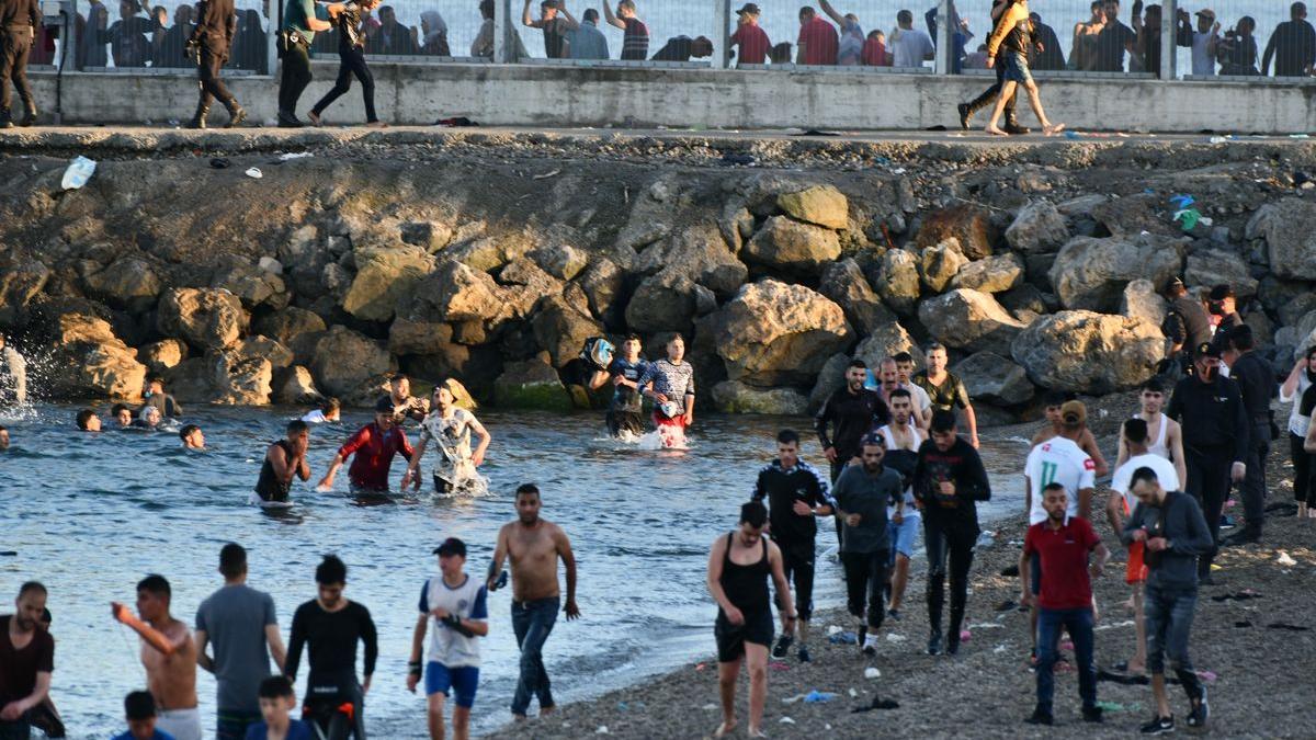Personas migrantes caminan por la playa del Tarajal, en Ceuta, el pasado 17 de mayo de 2021.