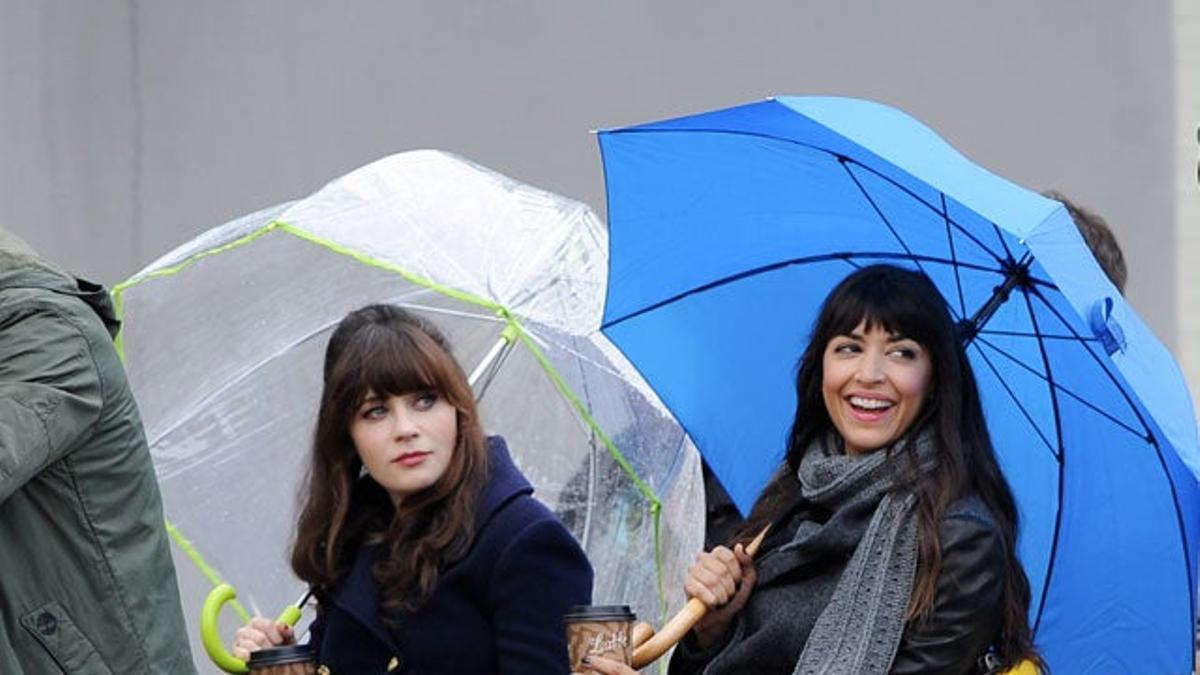 Zooey Deschanel y Hannah Simone en un pedicab con paraguas