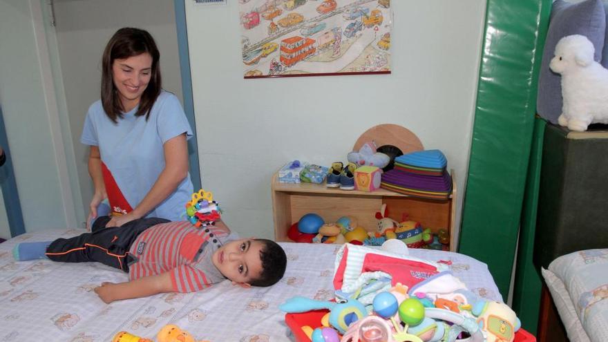 Una cuidadora atiende a un niño en el centro de Astus.