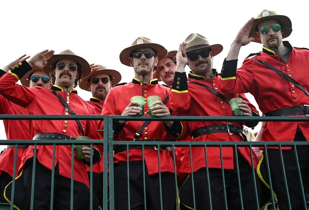 Un grupo de aficionados van disfrazados de la policia montada canadiense con su cerveza en la mano