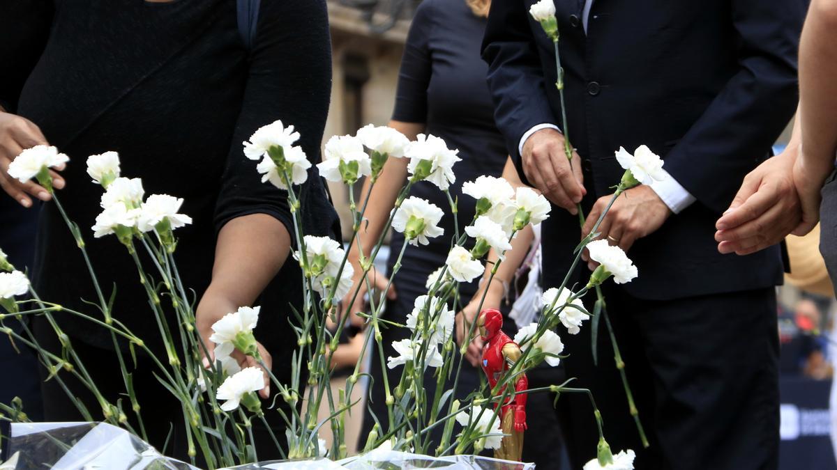 Pla detall de clavells blancs i una figura d&#039;Iron Man, que han dipositat familiars de les víctimes dels atemptats del 17-A per homenatjar els seus estimats, en l&#039;acte de commemoració dels cinc anys al pla de l&#039;Ós, a la Rambla de Barcelona.